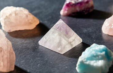 occult science, minerals and geology concept - quartz crystal pyramid and gem stones on slate...