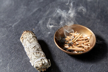 occult science and supernatural concept - white sage and cup with smoking matches