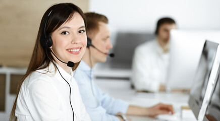 Group of diverse operators at work in call center. Beautiful asian woman sitting in headset at...