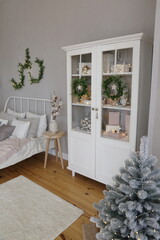 Wardrobe of white color against a gray textured wall in a room decorated for New Year