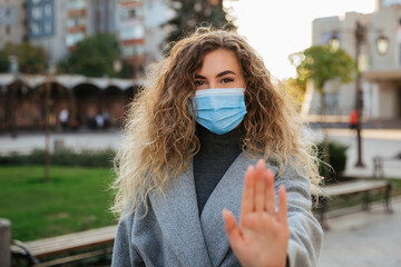 Keep your social distance. woman in virus protection face mask showing gesture Stop Infection. Coronavirus COVID-19 pandemic