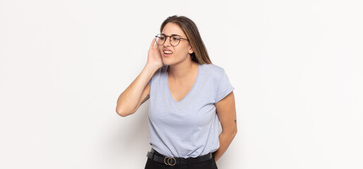 young blonde woman looking serious and curious, listening, trying to hear a secret conversation or...