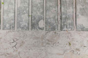 Wooden pathway on the sand beach surrounded with footprints