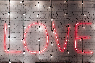 Red neon word Love written on brick wall