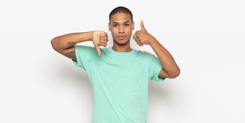 young black man feeling confused, clueless and unsure, weighting the good and bad in different...