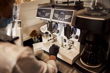 Female in gloves preparing coffee for guest of cafe