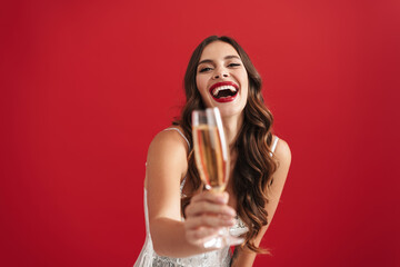 Happy girl in evening dress laughing and showing champagne glass