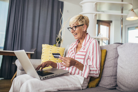 Smiling Mature Woman Shopping Online With Credit Card Using Laptop.