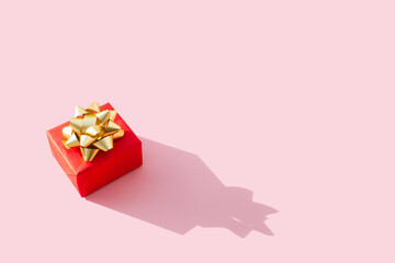 Shot of small red gift of pastel pink background. Holiday concept new year or Christmas gift box presents Xmas. Minimal composition. Flat lay. Top view. Copy space.