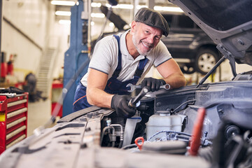 Cheerful auto mechanic working at car repair service station