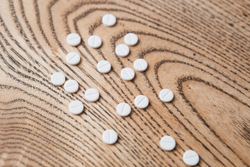 Fototapeta na wymiar white small round pills on a wooden background close-up. Pharmaceutical drugs for the treatment of diseases on a wooden table