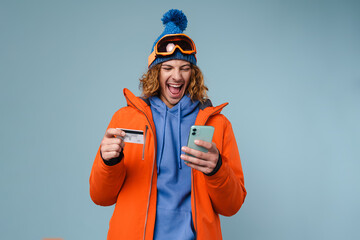 Young excited sportsman posing with credit card and cellphone