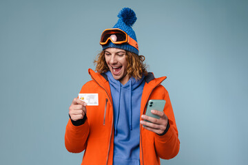 Young excited sportsman posing with credit card and cellphone