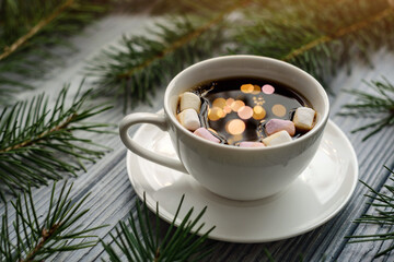 Reflection of lights of festive garlands in a cup of coffee with marshmallows.