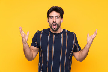Fototapeta premium Young handsome man with beard over isolated yellow background with surprise facial expression