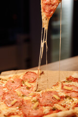 melted cheese stretches from a slice of pizza. Grabbing a slice of pizza with salami, mini corn and...