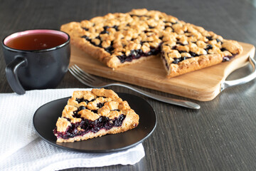 a plate with berry pie, blueberry pie on the background of the pie, next to there is a cup of tea