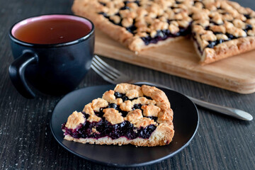 a plate with berry pie, blueberry pie on the background of the pie, next to there is a cup of tea