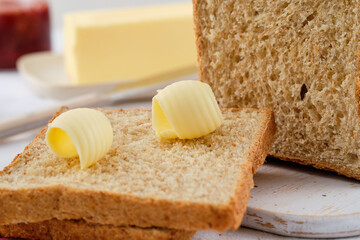 Butter curl on toast bread. Healthy breakfast with bran bread toast, butter and jam.