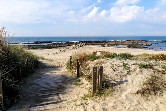 Beaches with clear, fine sand, with low vegetation, blue sea with rocks, cloudless sky, Afife city, parish of Viana do Castelo municipality, NUT III sub-region of Alto Minho, Portugal
