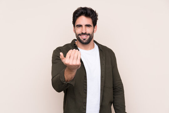 Young handsome man with beard over isolated background inviting to come with hand. Happy that you came