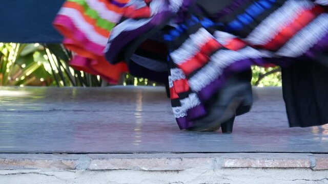Latino women in colourful traditional dresses dancing Jarabe tapatio, mexican national folk hat dance. Street performance of female hispanic ballet in multi colored ethnic skirts. Girls in costumes.