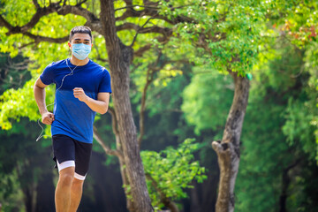  young man in face mask and jogging in the park during quarantine