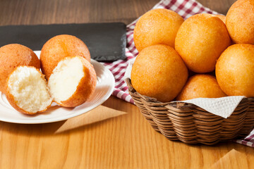 Buñuelos traditional Colombian food; Basket with tasty buñuelos on wooden background.