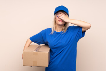 Young delivery woman over isolated background covering eyes by hands