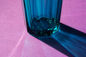 Glass with water on pink background. selective focus. concept of light refraction.