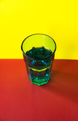 Glass with water on yellow and red background. selective focus. concept of light refraction. abstract object