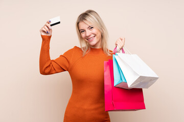 Fototapeta na wymiar Young blonde woman over isolated background holding shopping bags and a credit card