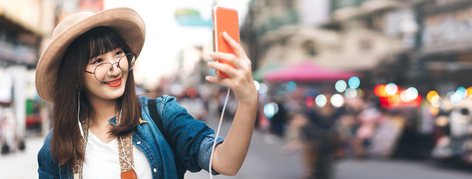 Young adult asian woman listen online streaming music and traveling at outdoor on day banner size background.