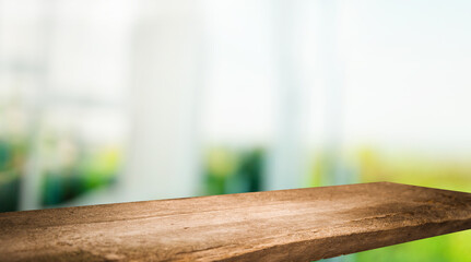 The top of the wooden table on the blur of the windowpane. Green color from a vegetable garden on the morning background. For product montage display.