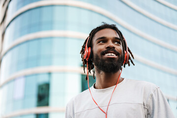 Cheerful african american guy listening music with headphones