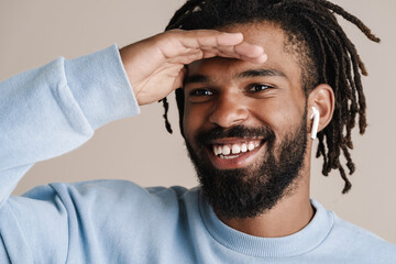 Obraz premium Cheerful african american guy in earphones looking aside