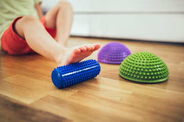 Flat feet correction exercise. Girl using spiked rubber roller