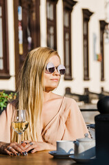 A fatal blonde in a black dress with hair in the wind looks piercingly into the distance - a self-confident woman in anticipation