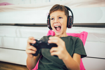 Little boy with gamepad playing video game at home