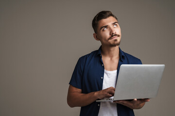 Image of serious handsome guy thinking while using laptop