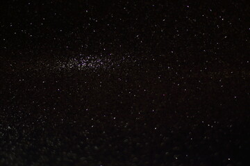 Black shiny glitter background, glowing blurred pattern for Christmas and New Year cards