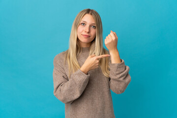 Young blonde woman isolated on blue background making the gesture of being late