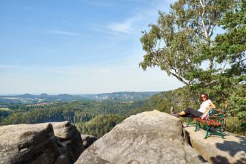 Black woman relaxing on top of a Mountain in the Elbsandstein Mountains, Saxon Switzerland, Germany.