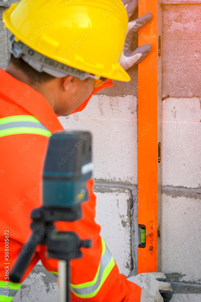 Poster a construction worker measuring the scene from the laser marking device to match the desired size