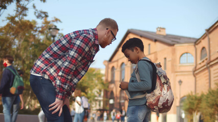 Side view of young male teacher scolding naughty african student outdoors