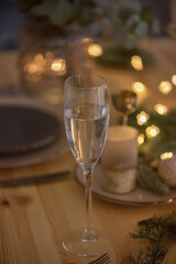 A glass of champagne in the background of the Christmas table and the lights of the Christmas tree