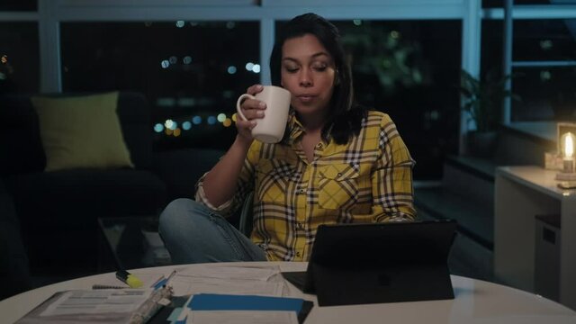 Multiethnic woman doing budget and counting money at home, girl checking dollars to pay utilities bill late at night. Young latin people reviewing invoice, planning family business and filing taxes