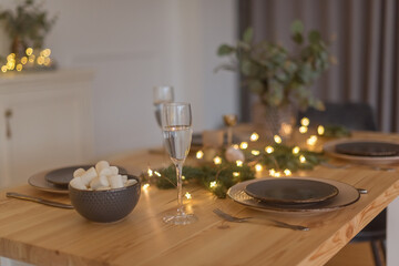 A glass of champagne in the background of the Christmas table and the lights of the Christmas tree