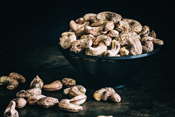 Raw unpeeled cashew nuts on a dark background