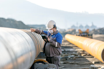 Technician is testing to welds of pipe with ultrasonic test method. It is a family of non-destructive testing techniques based on the propagation of ultrasonic waves in the object or material tested.